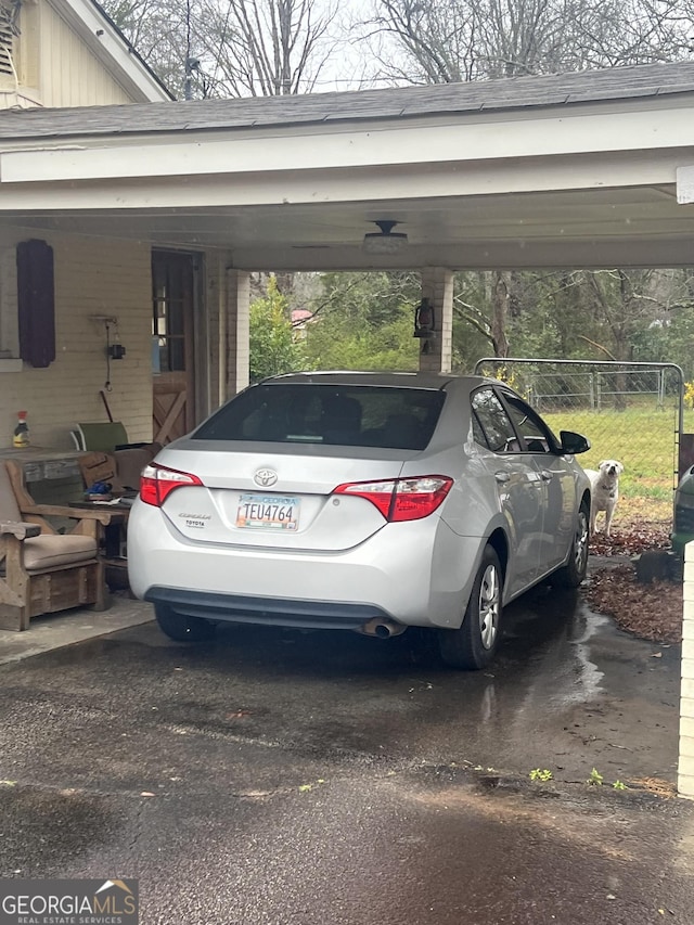 view of parking / parking lot with a carport and fence