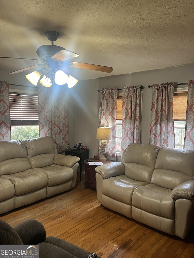 living room with a textured ceiling, ceiling fan, and hardwood / wood-style floors