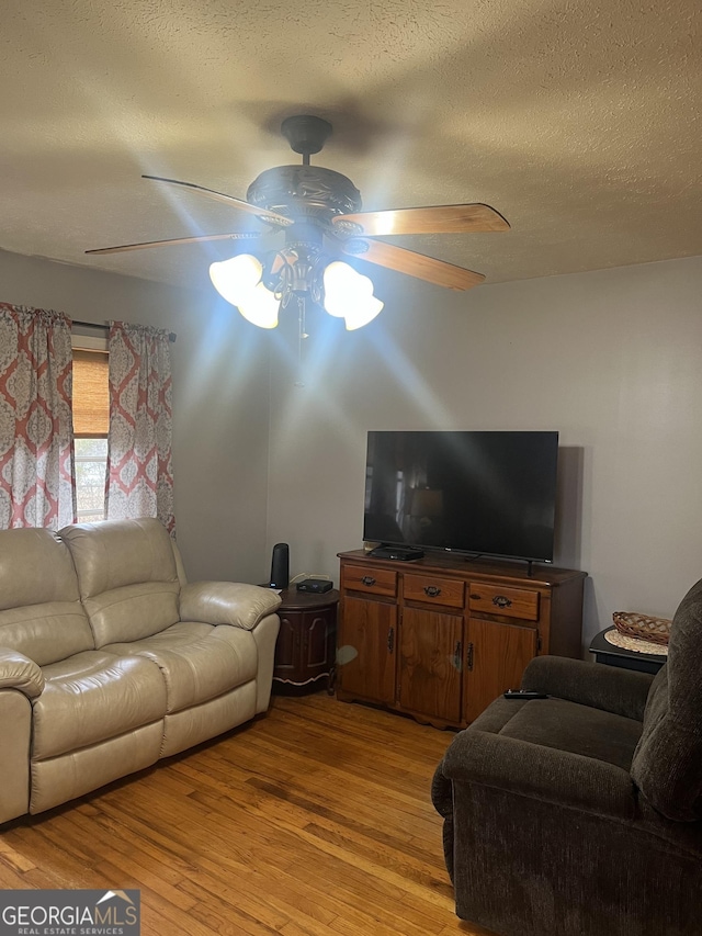 living room featuring a textured ceiling, light wood-style flooring, and ceiling fan