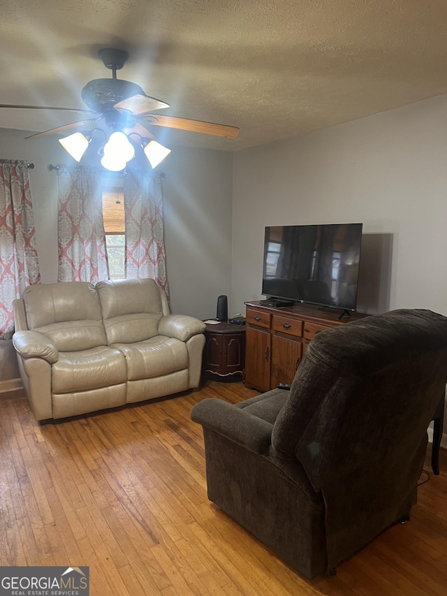 living room featuring a textured ceiling, light wood-style floors, and a ceiling fan