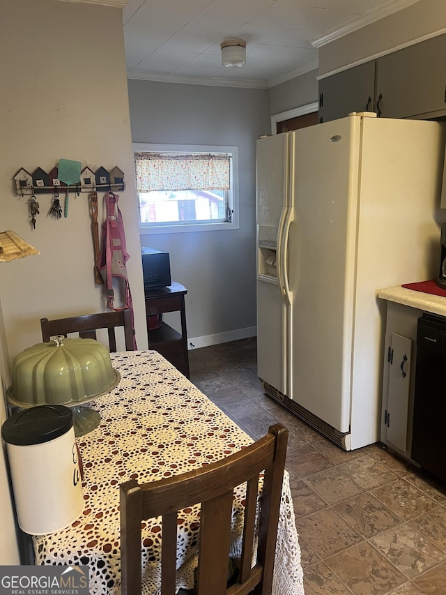 kitchen with stone finish flooring, white refrigerator with ice dispenser, ornamental molding, and dishwasher