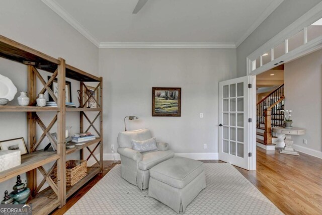 sitting room featuring stairs, baseboards, wood finished floors, and crown molding