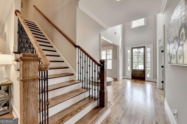 entrance foyer featuring stairs, a high ceiling, wood finished floors, and baseboards