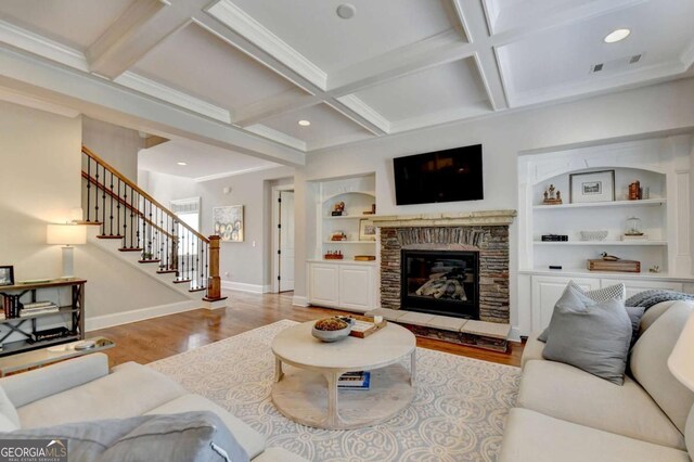 living room with baseboards, beamed ceiling, stairs, wood finished floors, and coffered ceiling