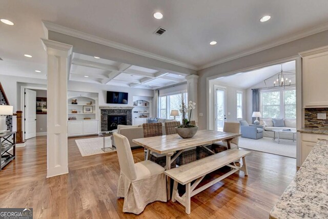 dining space with visible vents, a glass covered fireplace, plenty of natural light, coffered ceiling, and ornate columns