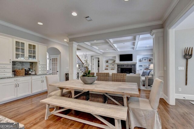 dining space featuring visible vents, light wood-style flooring, a fireplace, and beamed ceiling