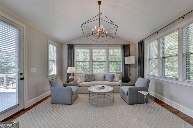 living room with an inviting chandelier, baseboards, lofted ceiling, and wood finished floors