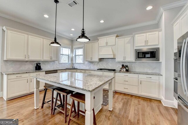 kitchen with visible vents, custom exhaust hood, white cabinets, stainless steel appliances, and a sink