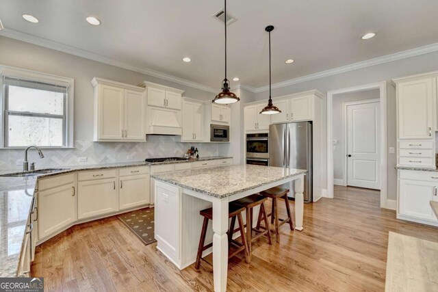 kitchen with visible vents, a breakfast bar, custom range hood, a sink, and appliances with stainless steel finishes