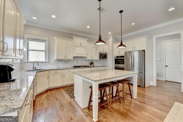 kitchen featuring premium range hood, a kitchen island, a sink, stainless steel appliances, and a kitchen bar