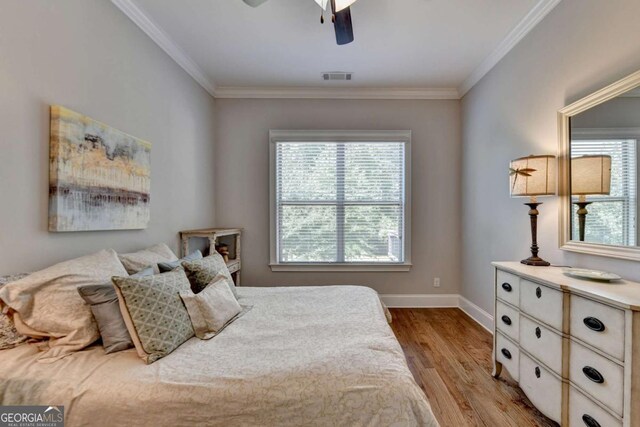 bedroom with wood finished floors, baseboards, visible vents, ceiling fan, and ornamental molding