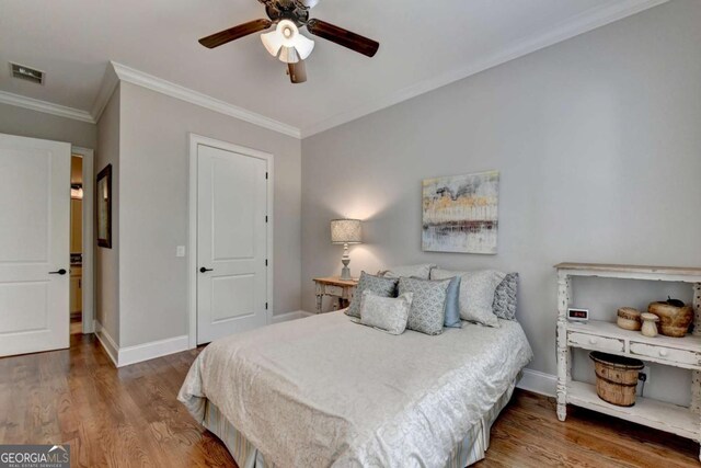 bedroom with ornamental molding, wood finished floors, visible vents, and baseboards