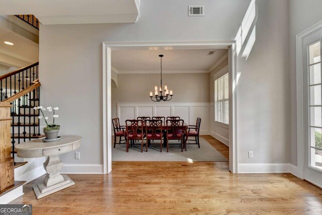 dining space featuring visible vents, a chandelier, stairway, ornamental molding, and light wood-style flooring