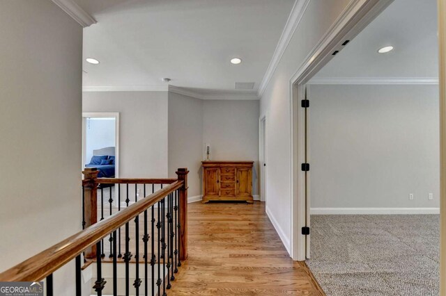 hall with an upstairs landing, recessed lighting, crown molding, and baseboards