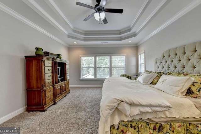 bedroom featuring baseboards, a raised ceiling, light colored carpet, and crown molding