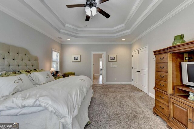 bedroom with light carpet, a raised ceiling, ensuite bathroom, crown molding, and baseboards