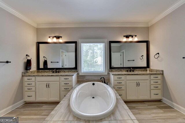 full bath with a sink, a garden tub, two vanities, and ornamental molding