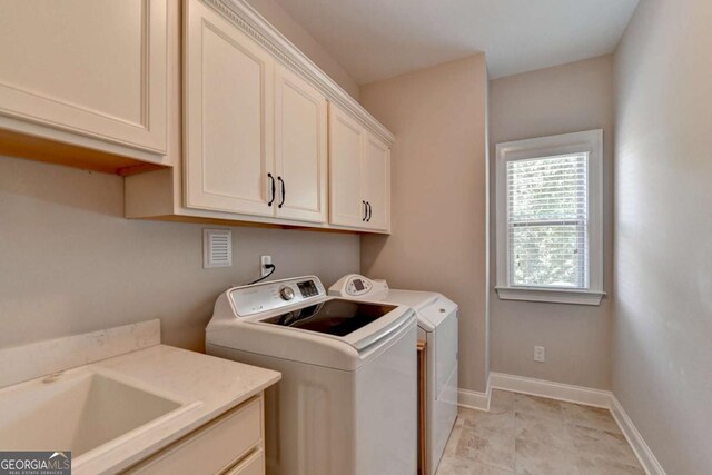 clothes washing area featuring a sink, baseboards, cabinet space, and washing machine and clothes dryer