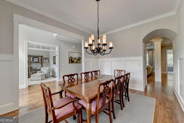 dining room with arched walkways, a chandelier, crown molding, and wood finished floors