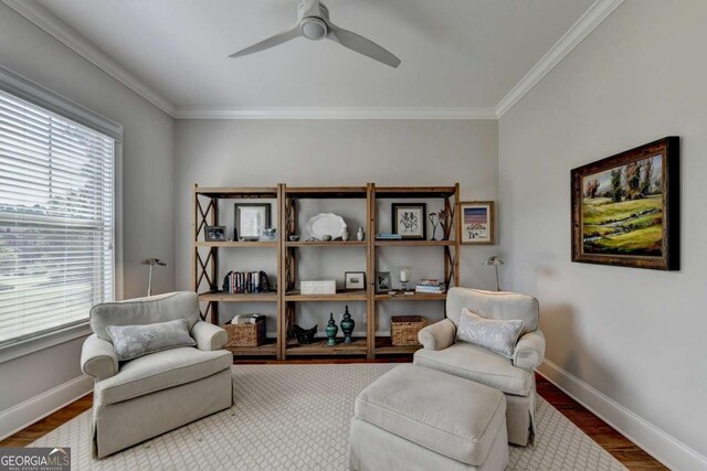 sitting room featuring wood finished floors, baseboards, ornamental molding, and a ceiling fan