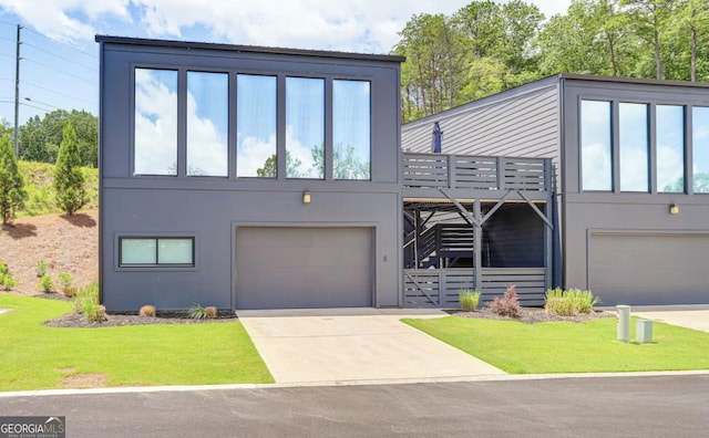 view of front of house featuring a front yard, an attached garage, driveway, and stucco siding