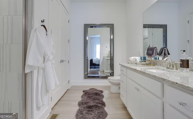 bathroom with vanity, toilet, wood finished floors, and visible vents