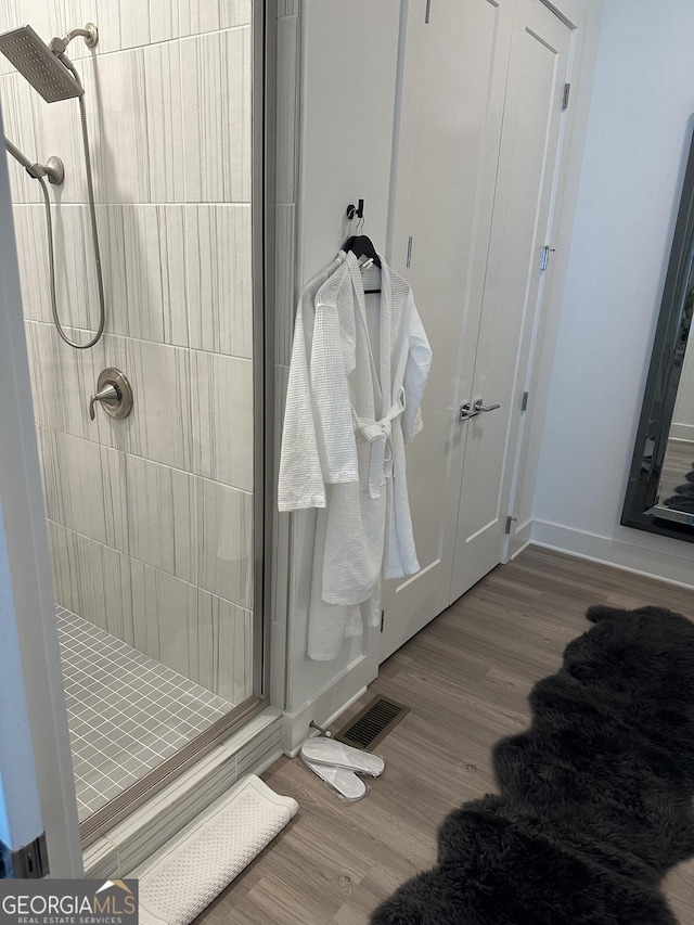 bathroom with visible vents, a shower stall, baseboards, and wood finished floors