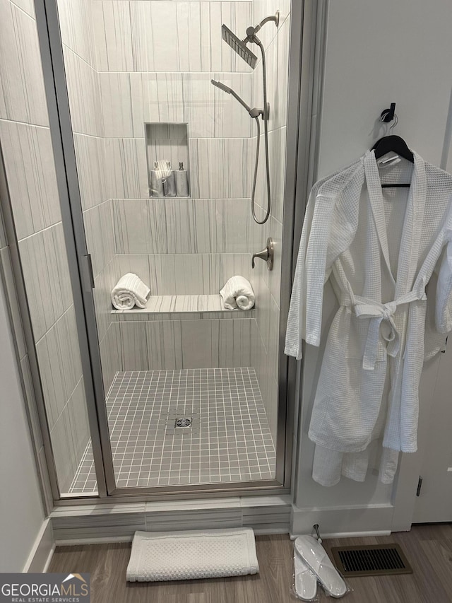 full bath featuring visible vents, a shower stall, and wood finished floors