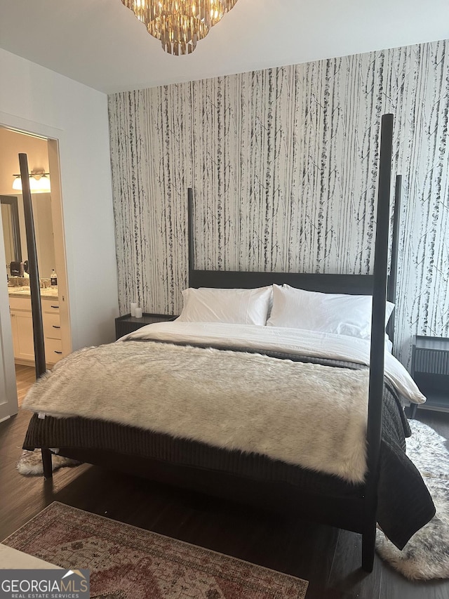 bedroom featuring a notable chandelier, ensuite bathroom, and wood finished floors