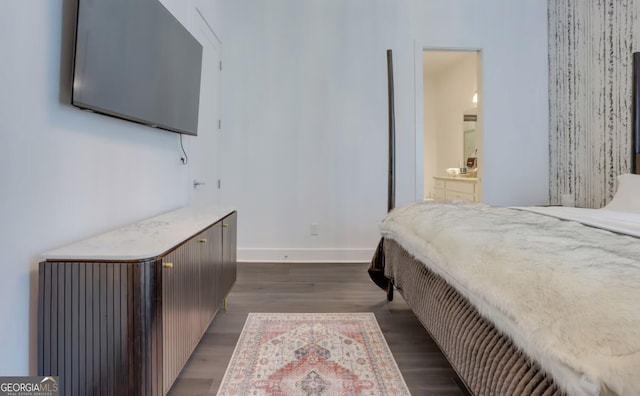 bedroom featuring dark wood finished floors, ensuite bath, and baseboards