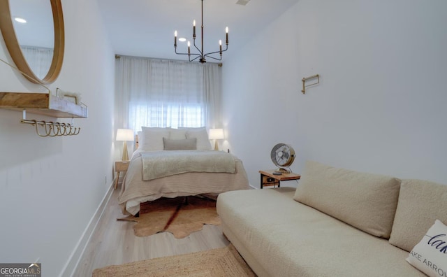 bedroom with a notable chandelier, baseboards, and wood finished floors