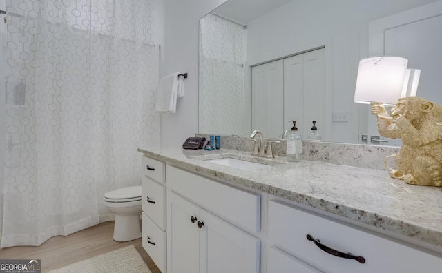 bathroom with curtained shower, toilet, wood finished floors, and vanity