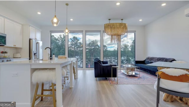 interior space with recessed lighting, a wall mounted air conditioner, and light wood-style floors