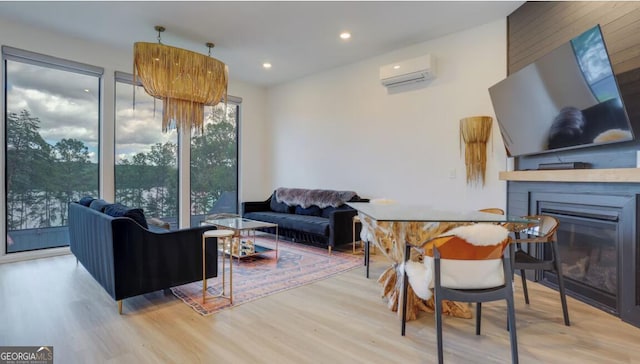 living room with a glass covered fireplace, an AC wall unit, wood finished floors, and recessed lighting