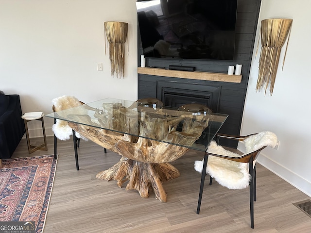 interior space with wood finished floors, a fireplace, baseboards, and visible vents