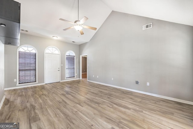 empty room featuring baseboards, visible vents, high vaulted ceiling, ceiling fan, and light wood-type flooring