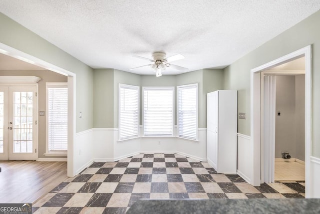 empty room featuring french doors, a textured ceiling, and a ceiling fan