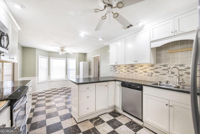 kitchen featuring light floors, a peninsula, a sink, stainless steel appliances, and white cabinets