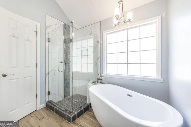 full bath featuring a soaking tub, a chandelier, a marble finish shower, and wood finish floors