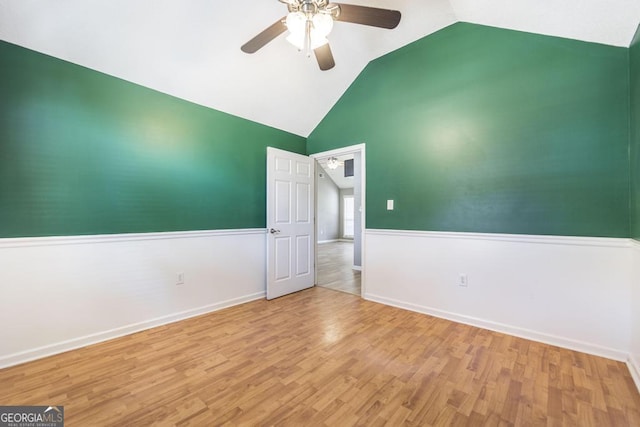 spare room with vaulted ceiling, wood finished floors, baseboards, and ceiling fan