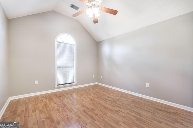 unfurnished room with visible vents, light wood-style flooring, a ceiling fan, baseboards, and vaulted ceiling