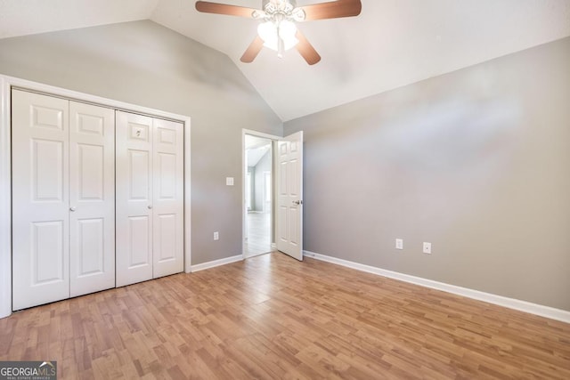 unfurnished bedroom with baseboards, light wood finished floors, ceiling fan, vaulted ceiling, and a closet