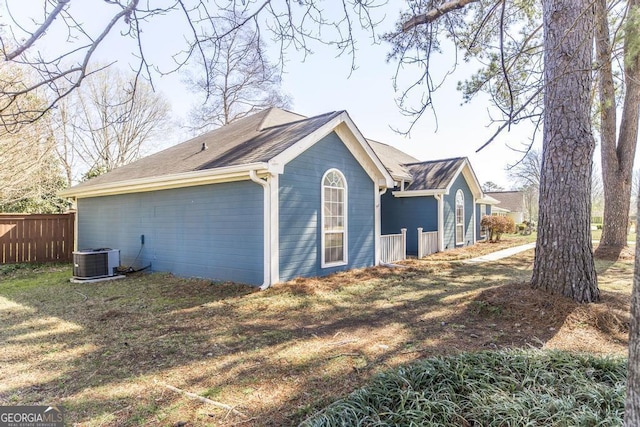 view of side of home featuring cooling unit, a yard, and fence