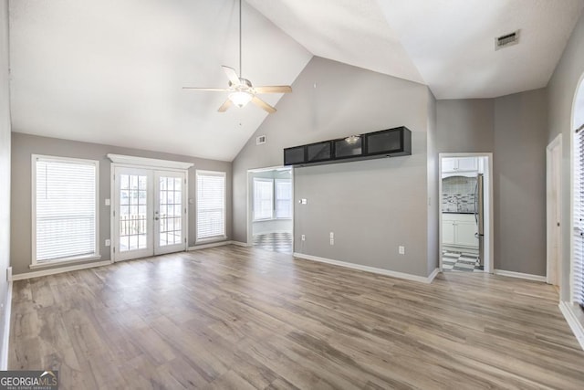 unfurnished living room with french doors, light wood-style floors, visible vents, and high vaulted ceiling