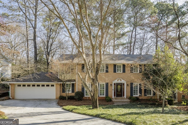 colonial house with aphalt driveway, a garage, and a front lawn