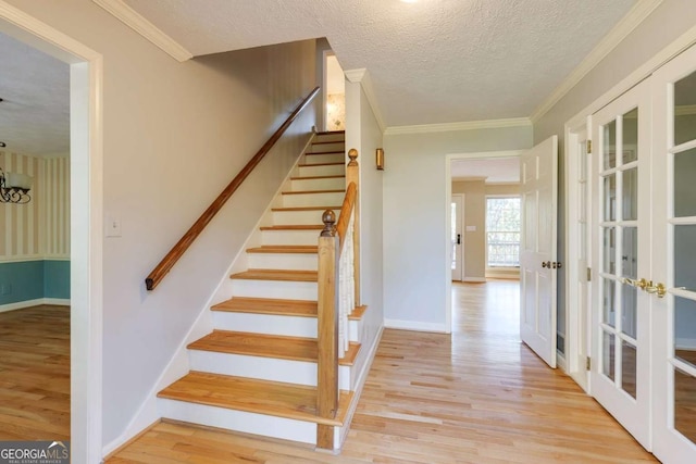 stairs featuring wood finished floors, ornamental molding, french doors, and a textured ceiling