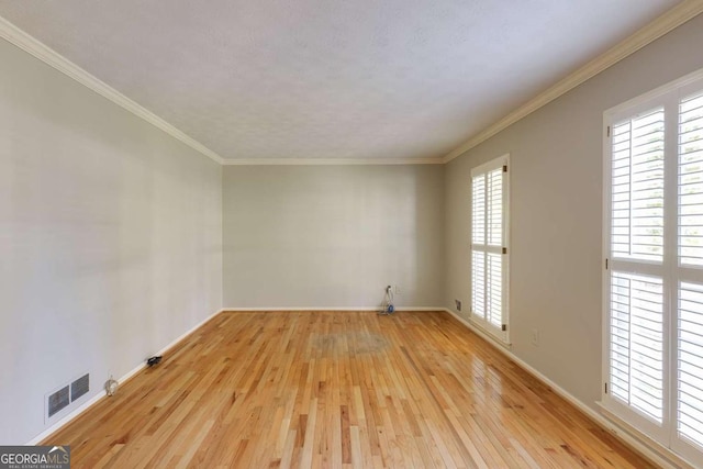 unfurnished room with crown molding, light wood-style flooring, baseboards, and visible vents