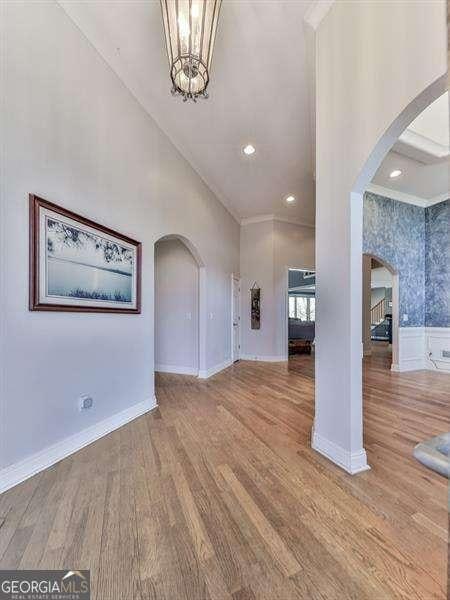 interior space featuring arched walkways, a high ceiling, baseboards, and wood finished floors