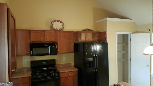 kitchen featuring brown cabinetry, black appliances, light countertops, and vaulted ceiling