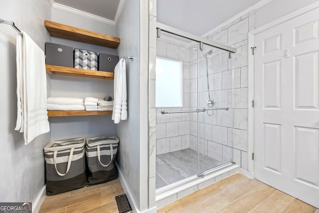 bathroom with wood finish floors, visible vents, ornamental molding, and a shower stall